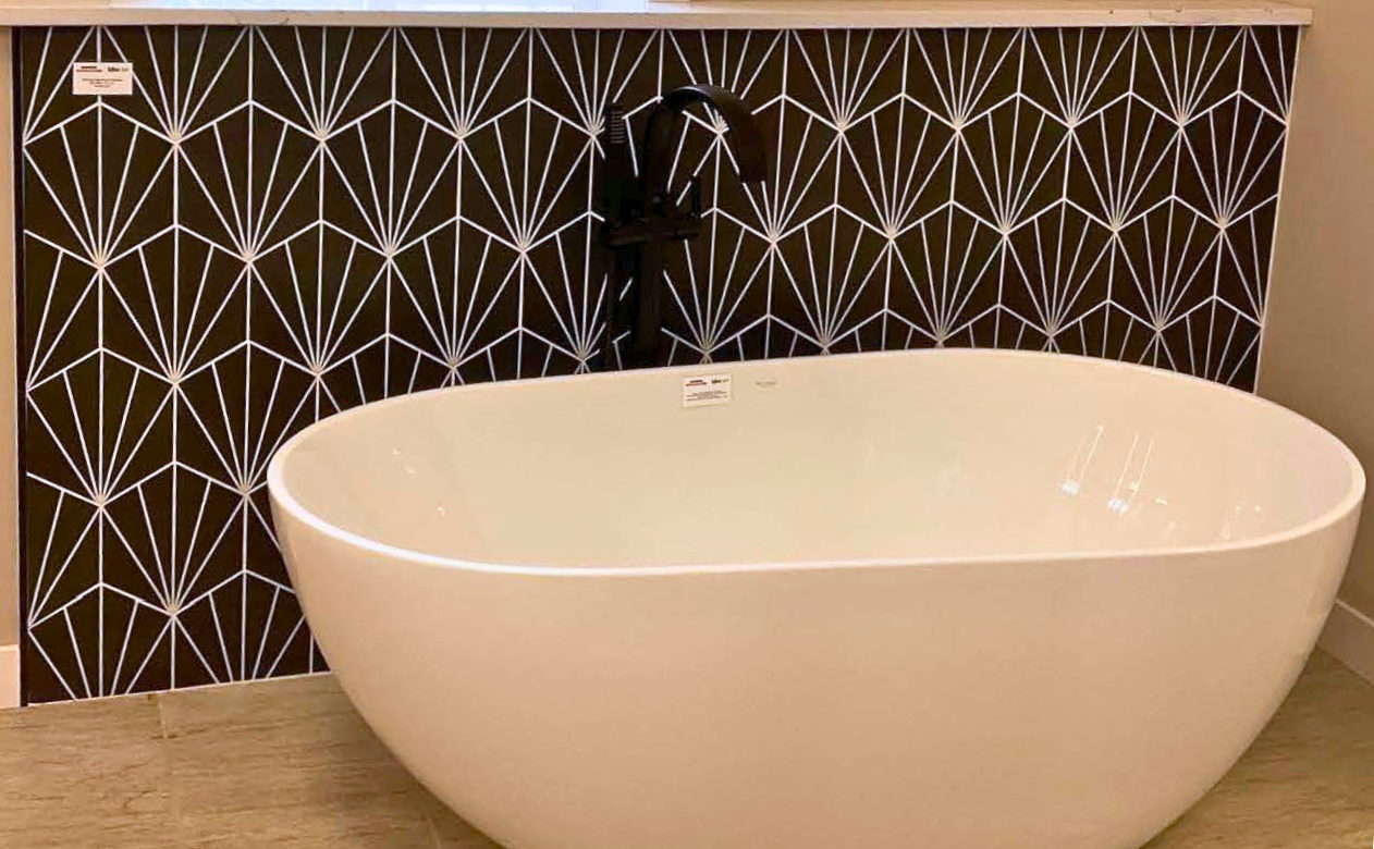 Black and white tile bathtub surround behind a free-standing tub