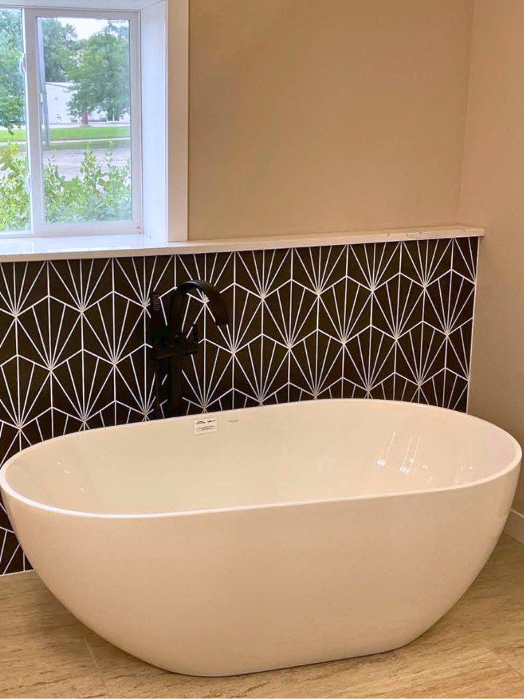 Black and white tile bathtub surround behind a free-standing tub